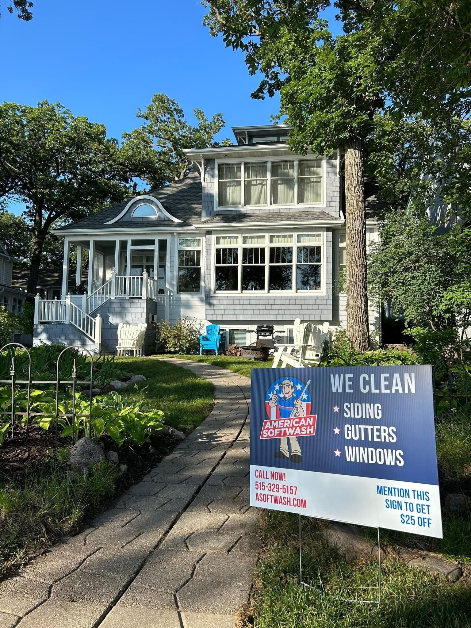 House with front yard and a lawn sign advertising clean siding, gutters, and windows.