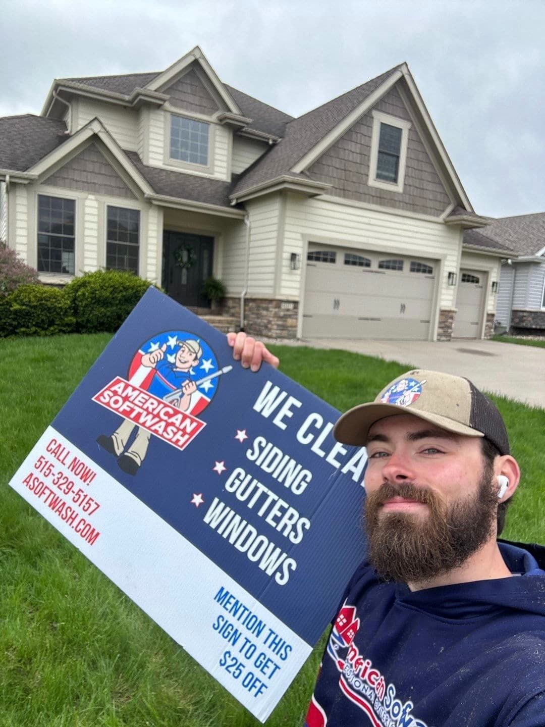 Man holding a roofing sign in front of a suburban house, promoting siding, gutters, and windows.