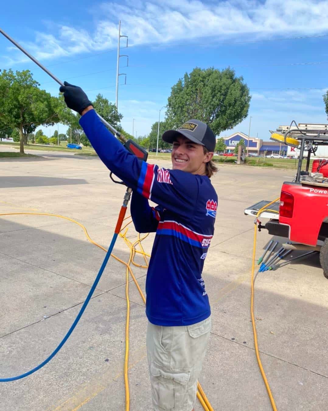 Person in blue shirt and cap holding a fishing rod or line outdoors on a paved lot.