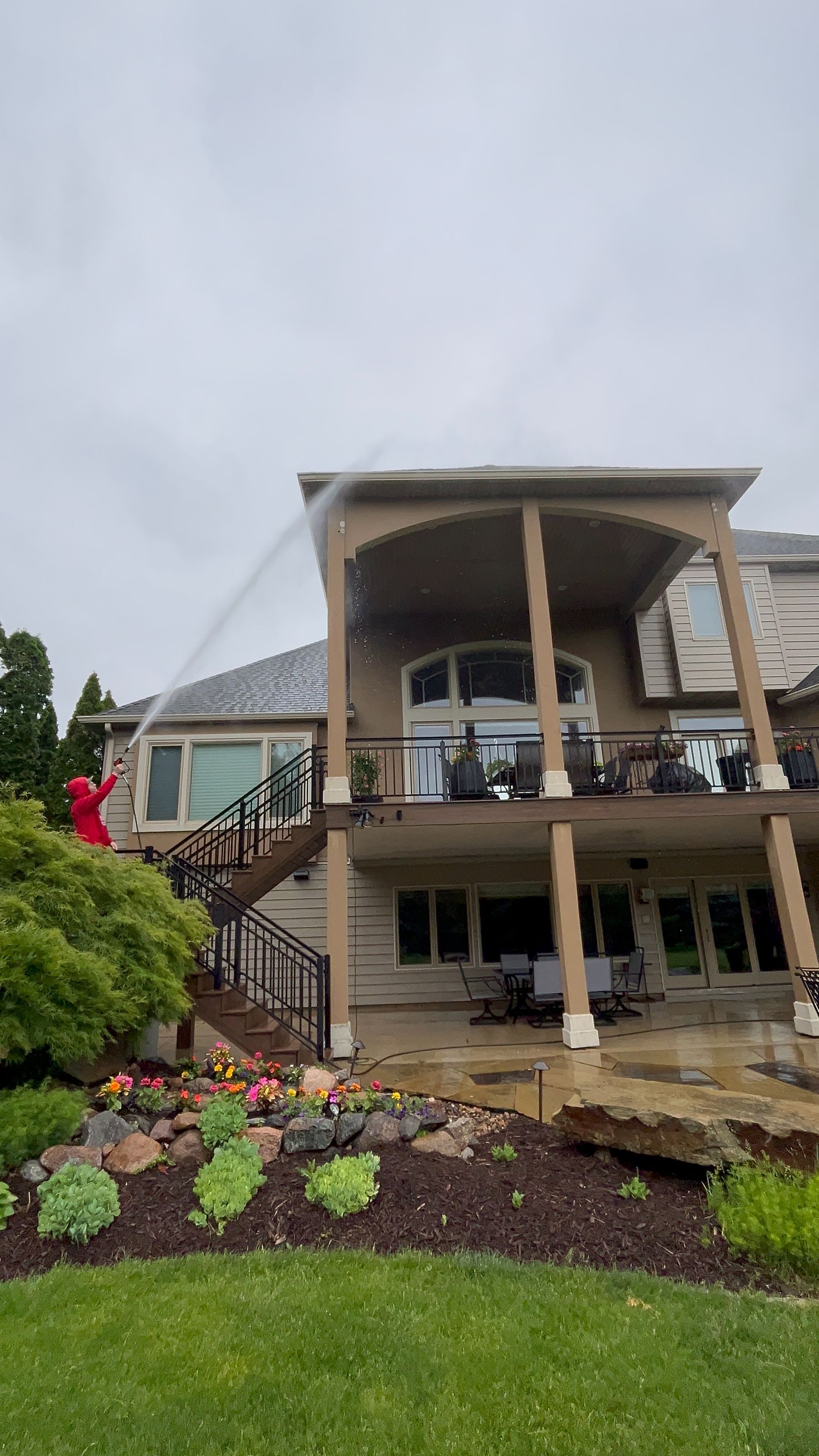 Modern building with a curved balcony, columns, and landscaped flower bed in front