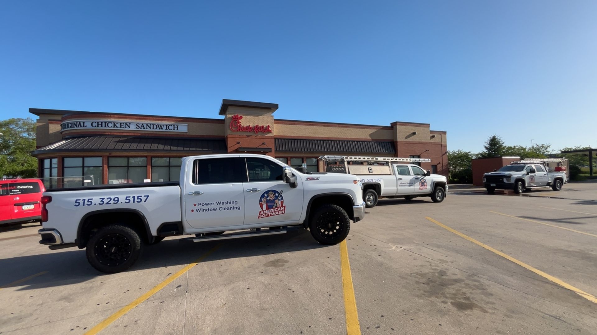 White service pickup trucks parked outside a storefront on a sunny day.