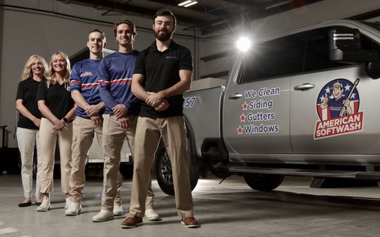 Four people stand beside a van with an “American Red Cross” logo in a parking lot at night.