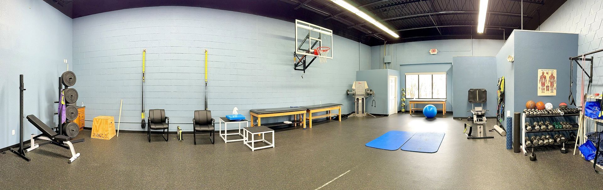 A panoramic view of a gym with a basketball hoop on the wall