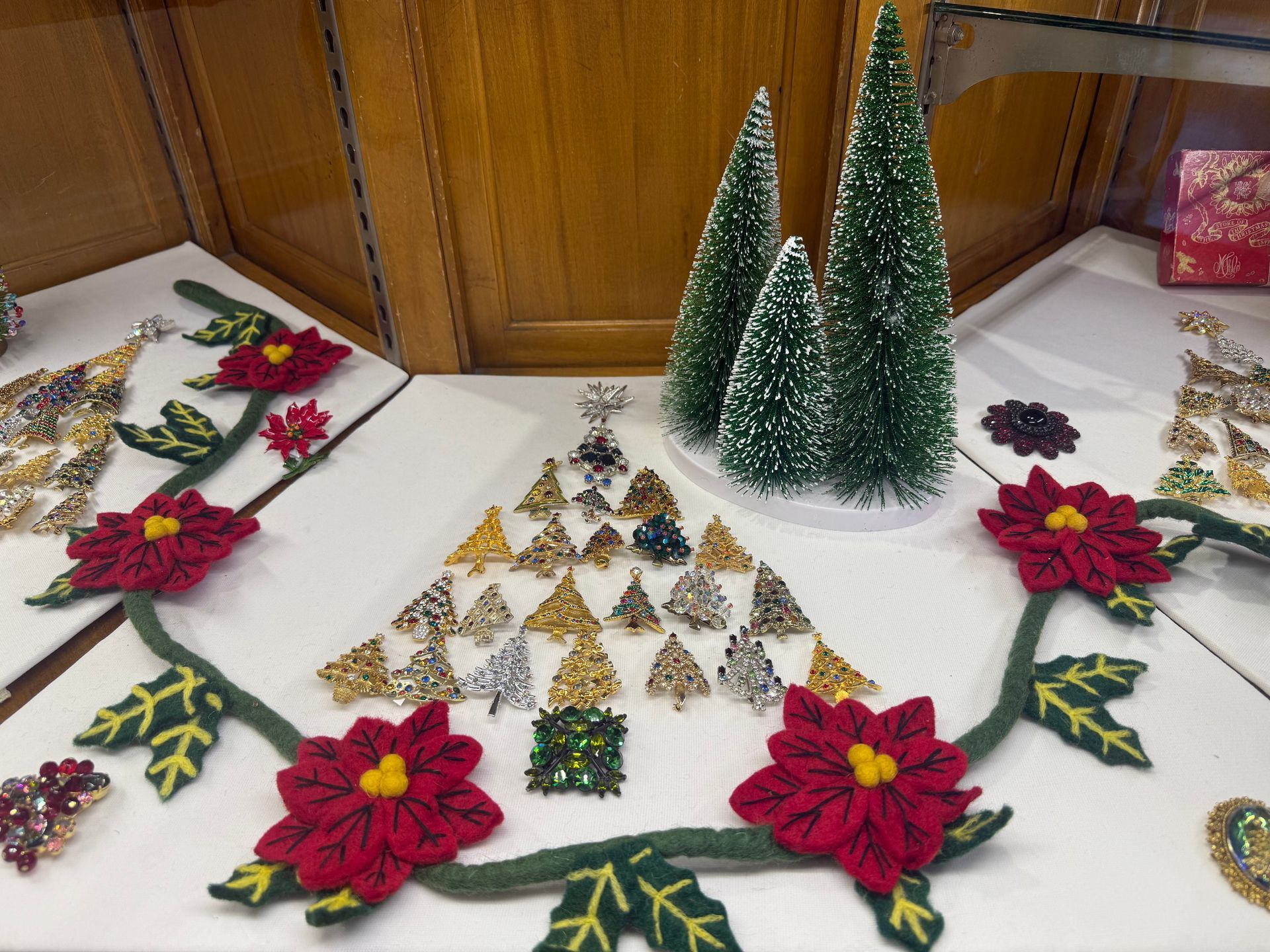 Jewelry display with Christmas tree ornaments and poinsettia garland.