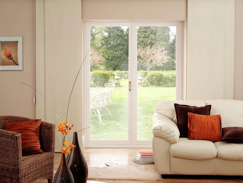A living room with a couch , chair , vases and sliding glass doors.