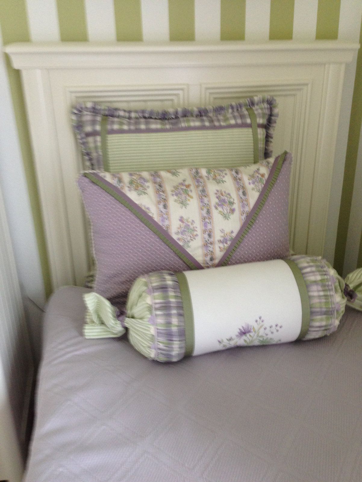 A bed with a purple pillow and a green pillow on it.