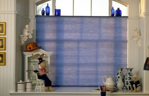 A window with a blue blind and a stuffed animal sitting on a stool