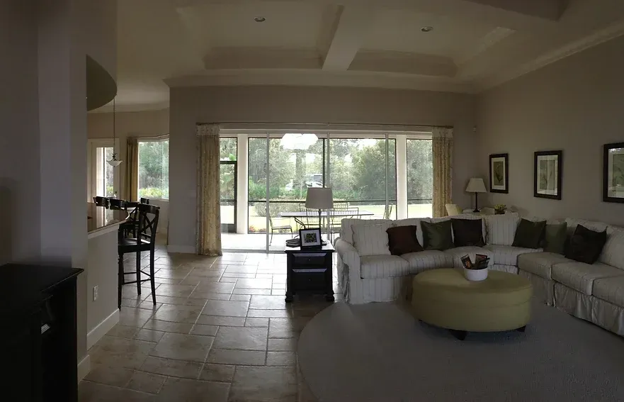 A living room with a large sectional couch and a green ottoman