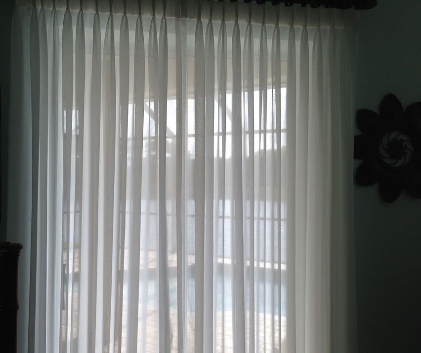 A white curtain is hanging on a sliding glass door in a living room.