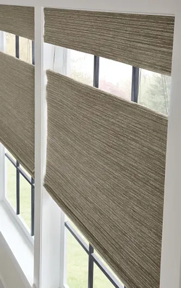 A pair of roman shades on a window in a room.