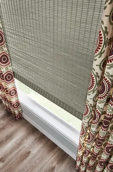 A close up of a window with a blind and curtains.