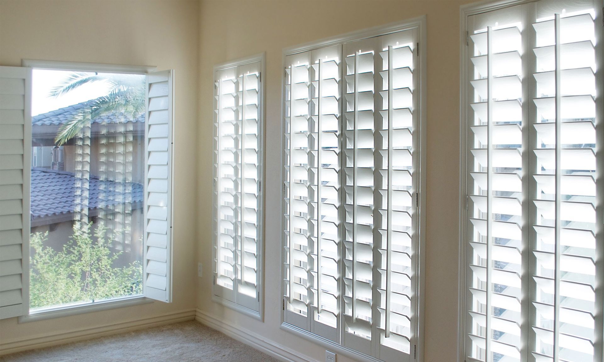 A room with a lot of white shutters on the windows