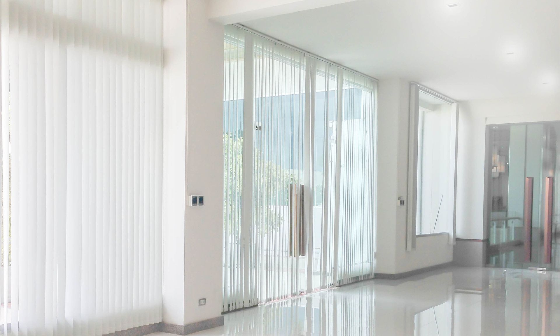 A large empty room with a lot of windows and curtains.