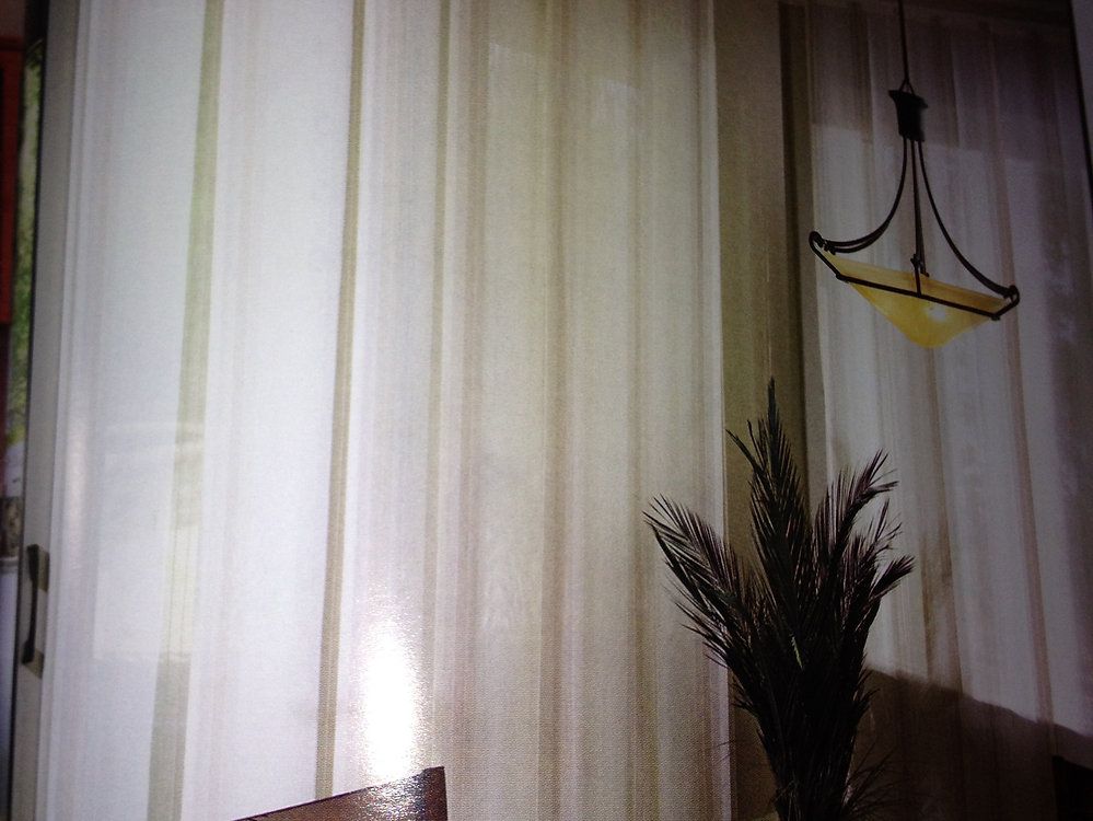 A room with white curtains and a lamp hanging from the ceiling