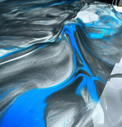 Swirling epoxy floor with blue, silver, and black pigments creating a marbled effect.