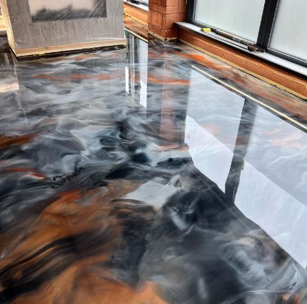 Metallic epoxy flooring in shades of gray, black, white, and copper reflects natural light.