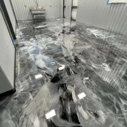 Metallic epoxy floor with swirling shades of gray and white in a warehouse.