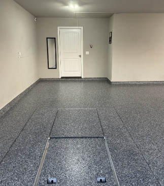 Garage interior with gray speckled floor, white door, and neutral walls.