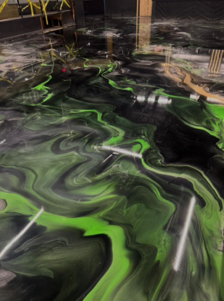Black and green epoxy floor with swirling patterns, possibly in a construction setting.
