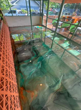 Green and orange epoxy floor on a patio, viewed from above, with an orange railing on the left.