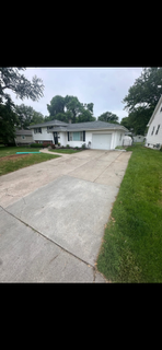 Suburban house with a wide concrete driveway and green lawn on a cloudy day