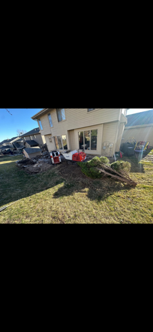 Backyard patio with lawn equipment, a red cooler, and landscaping debris beside a house.