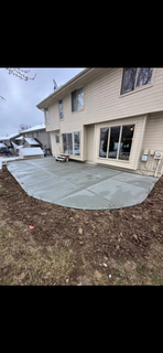 Backyard patio with fresh concrete slab beside a beige house and sliding glass doors