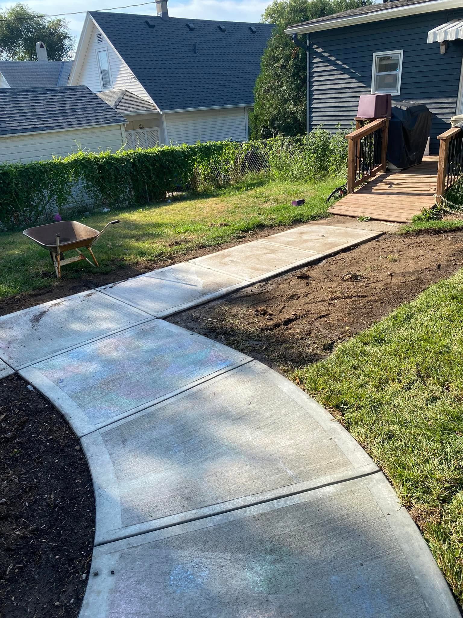 A concrete walkway is being built in the backyard of a house.