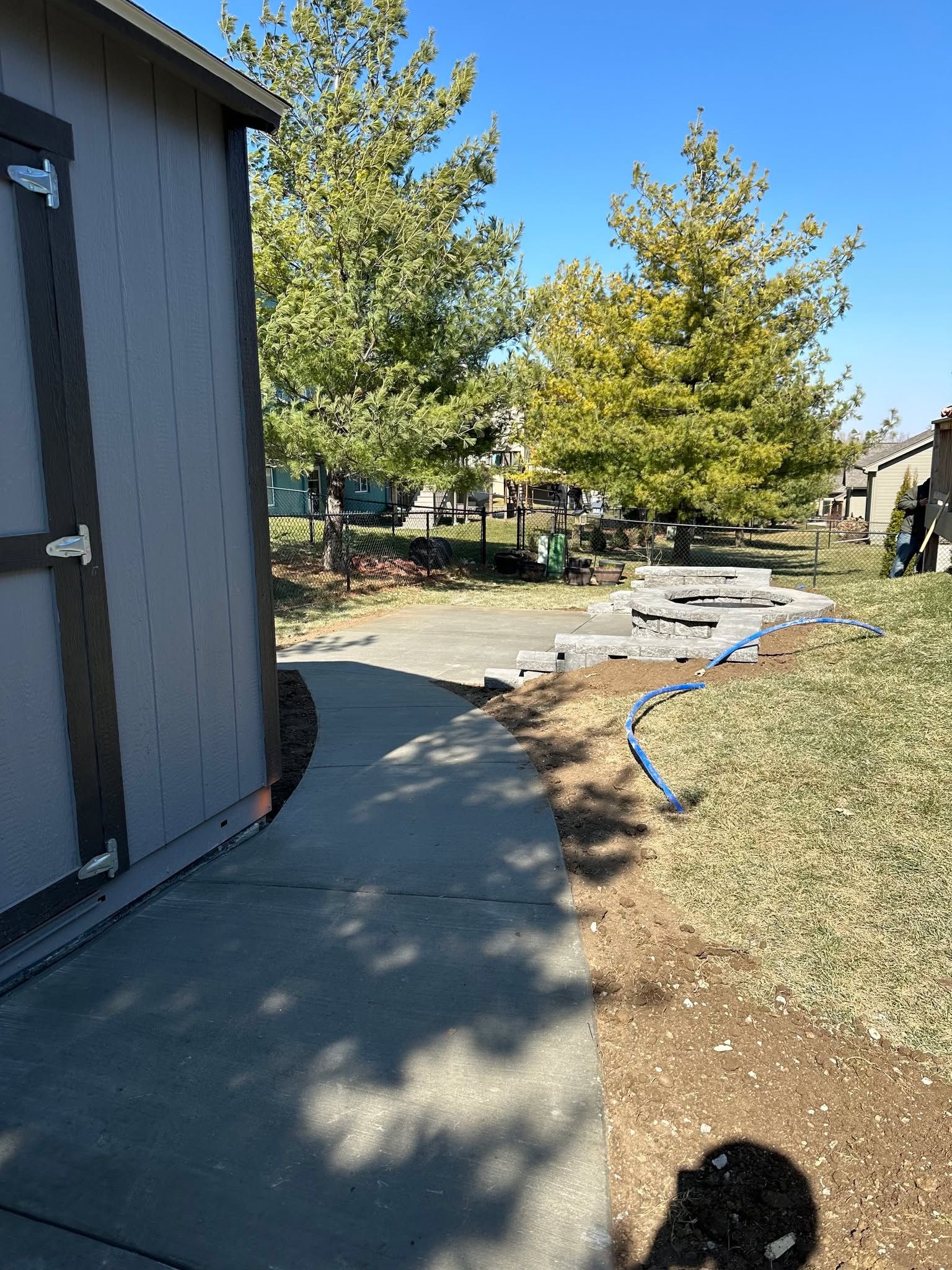 A dog is walking down a sidewalk next to a shed.
