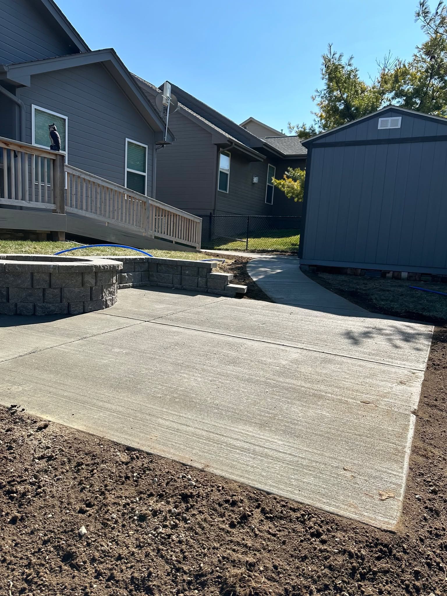 A concrete walkway leading to a shed in front of a house.