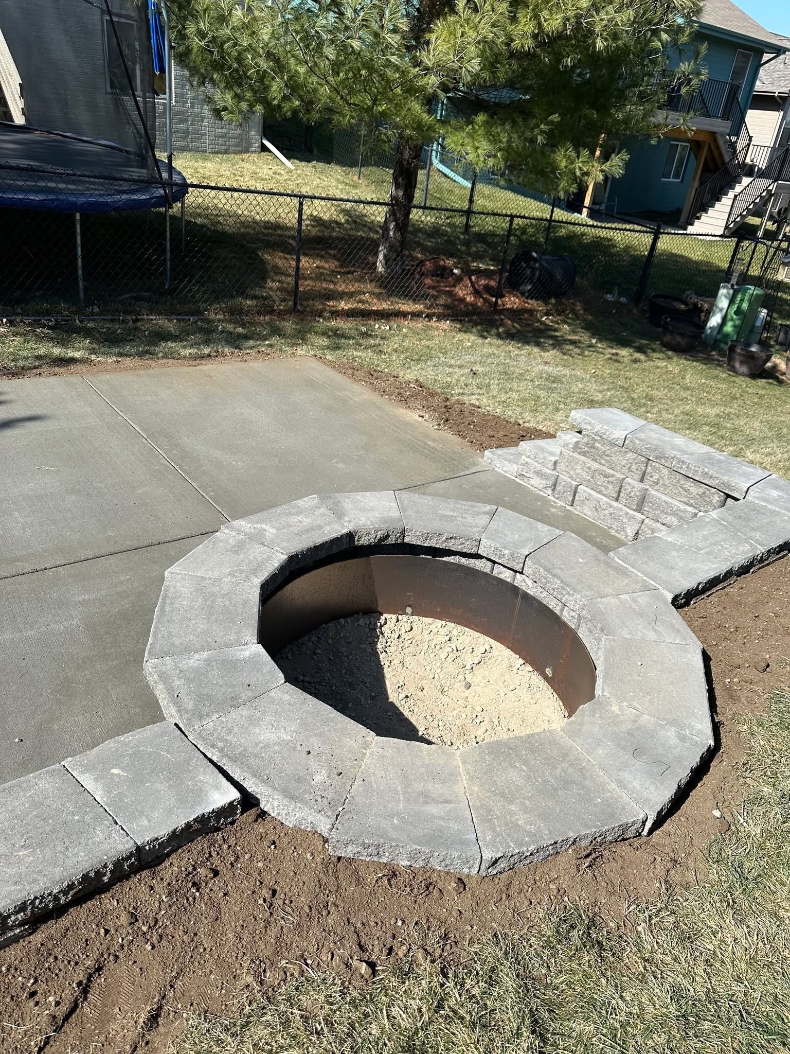 A fire pit is being built in the middle of a concrete patio.