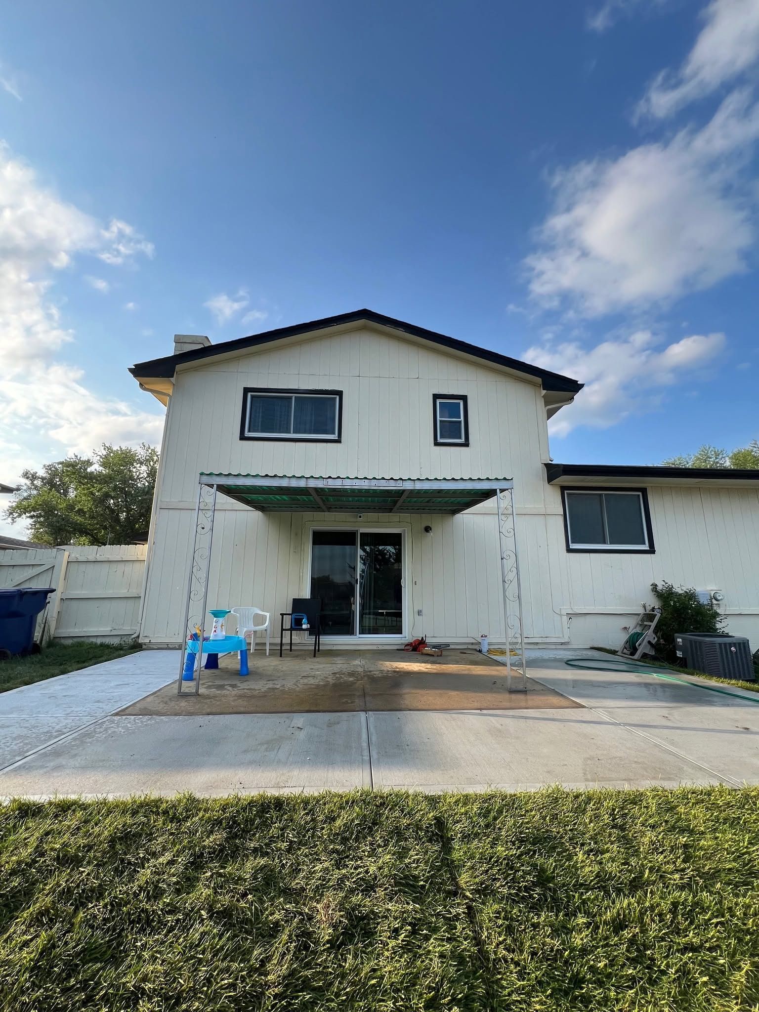 A white house with a sliding glass door is being painted.