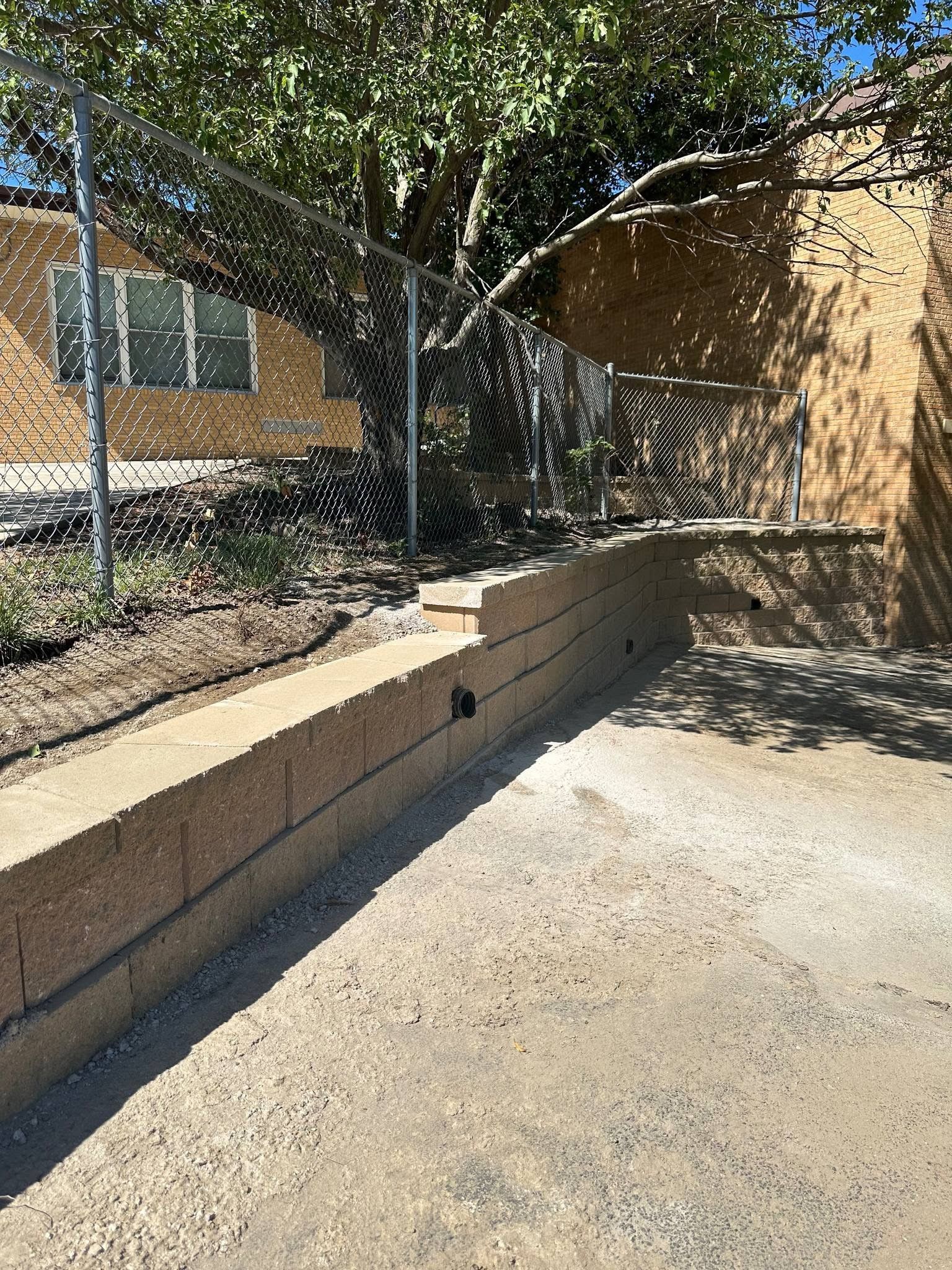 There is a fence around the pool and a tree in the background.