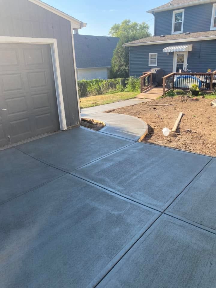 A concrete driveway next to a garage and a house.