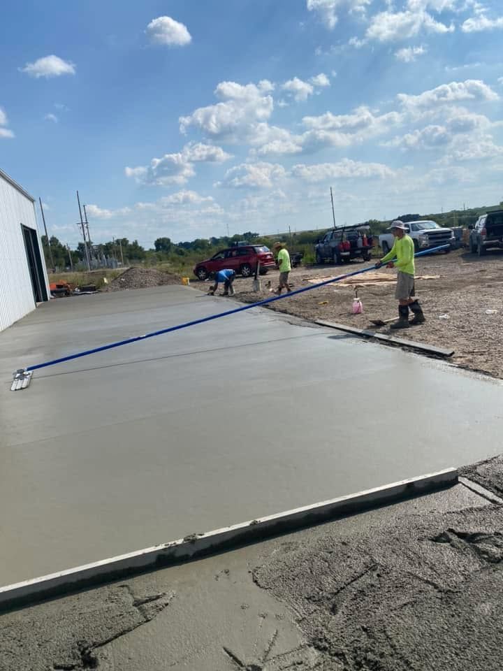 A group of construction workers are working on a concrete driveway.