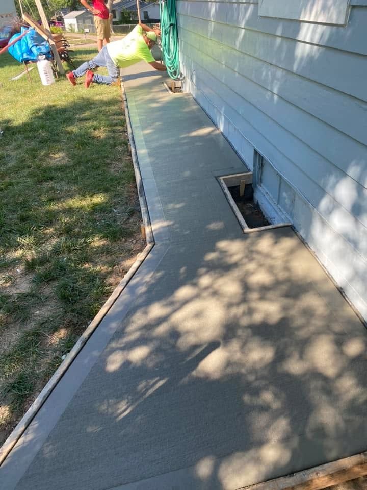 A concrete walkway is being built in front of a house.