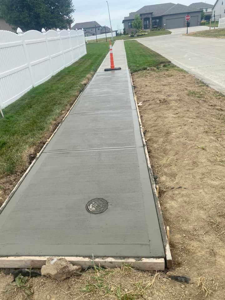 A concrete sidewalk is being built next to a white fence.