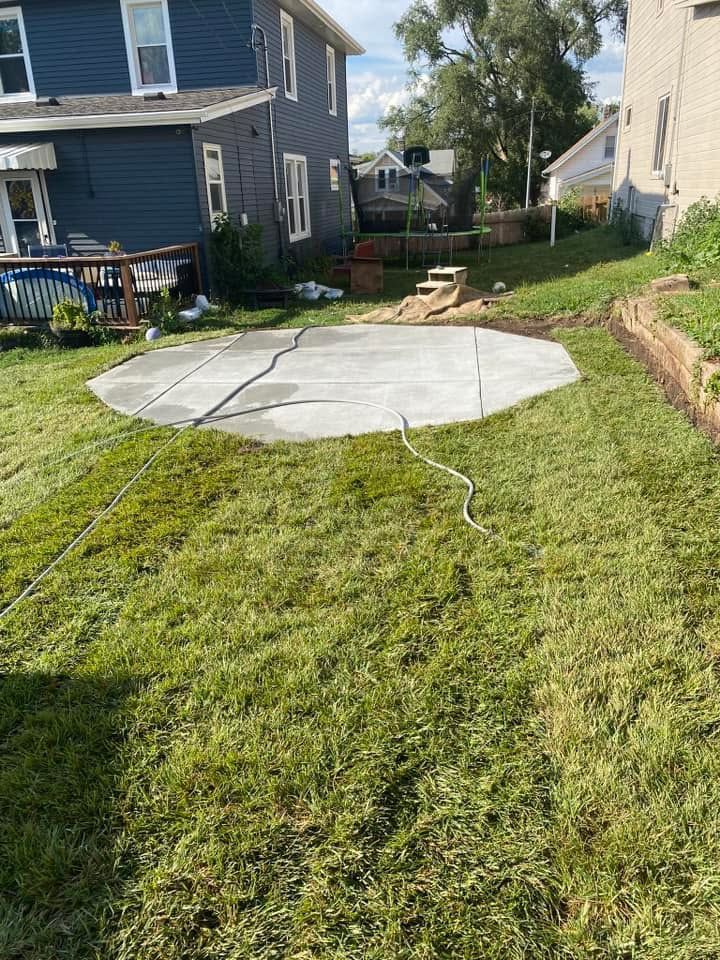 A concrete patio is being built in the backyard of a house.