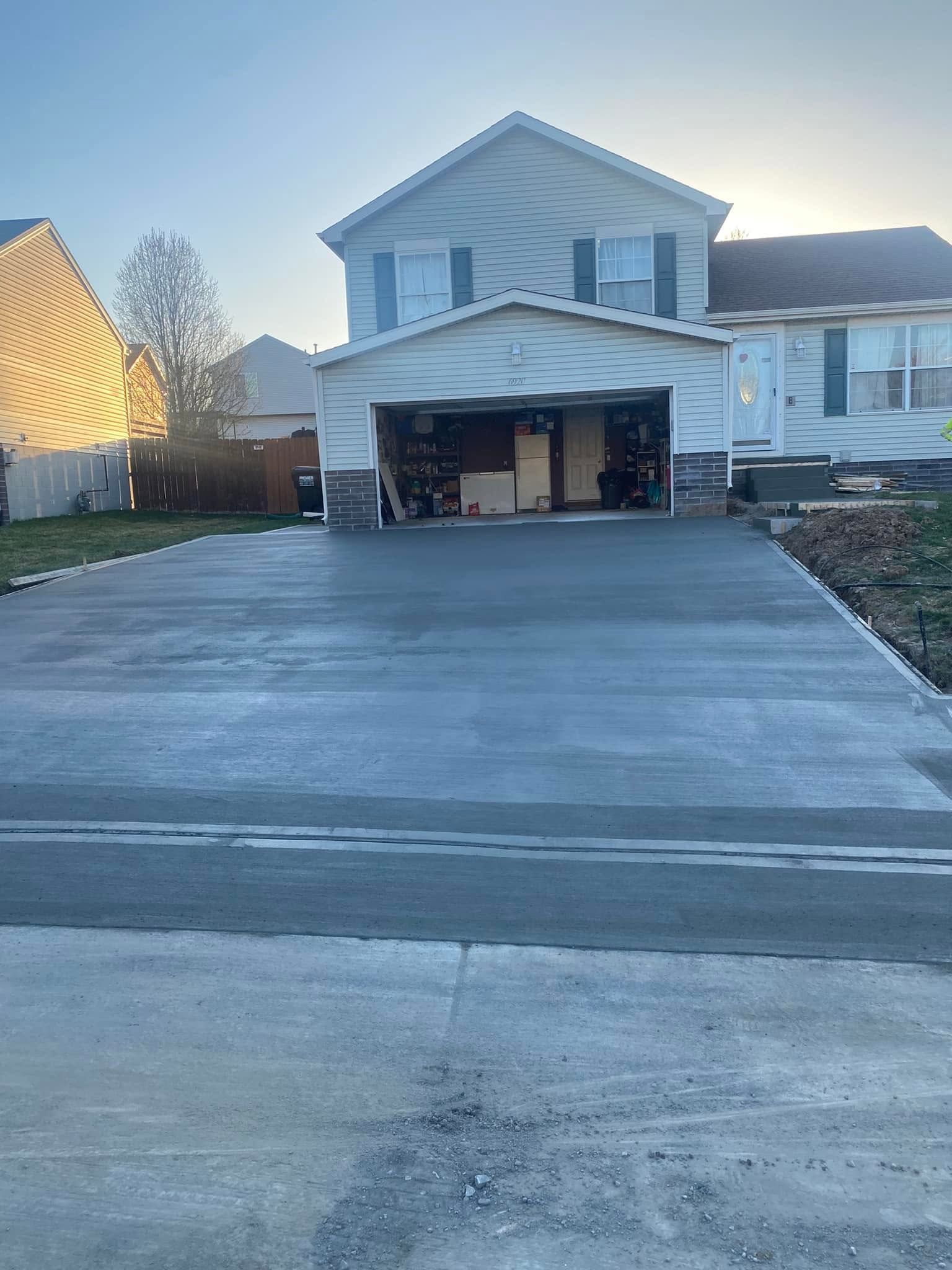 A house with a garage and a concrete driveway in front of it.