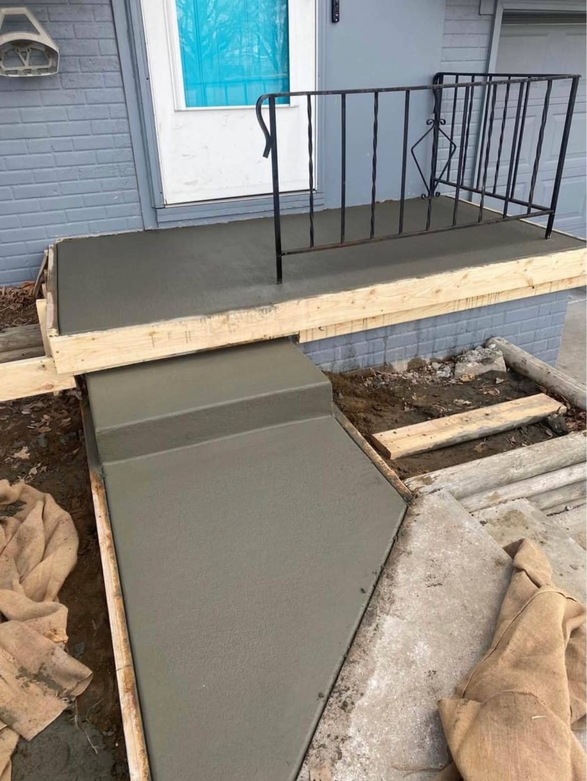 A concrete walkway is being built in front of a house.