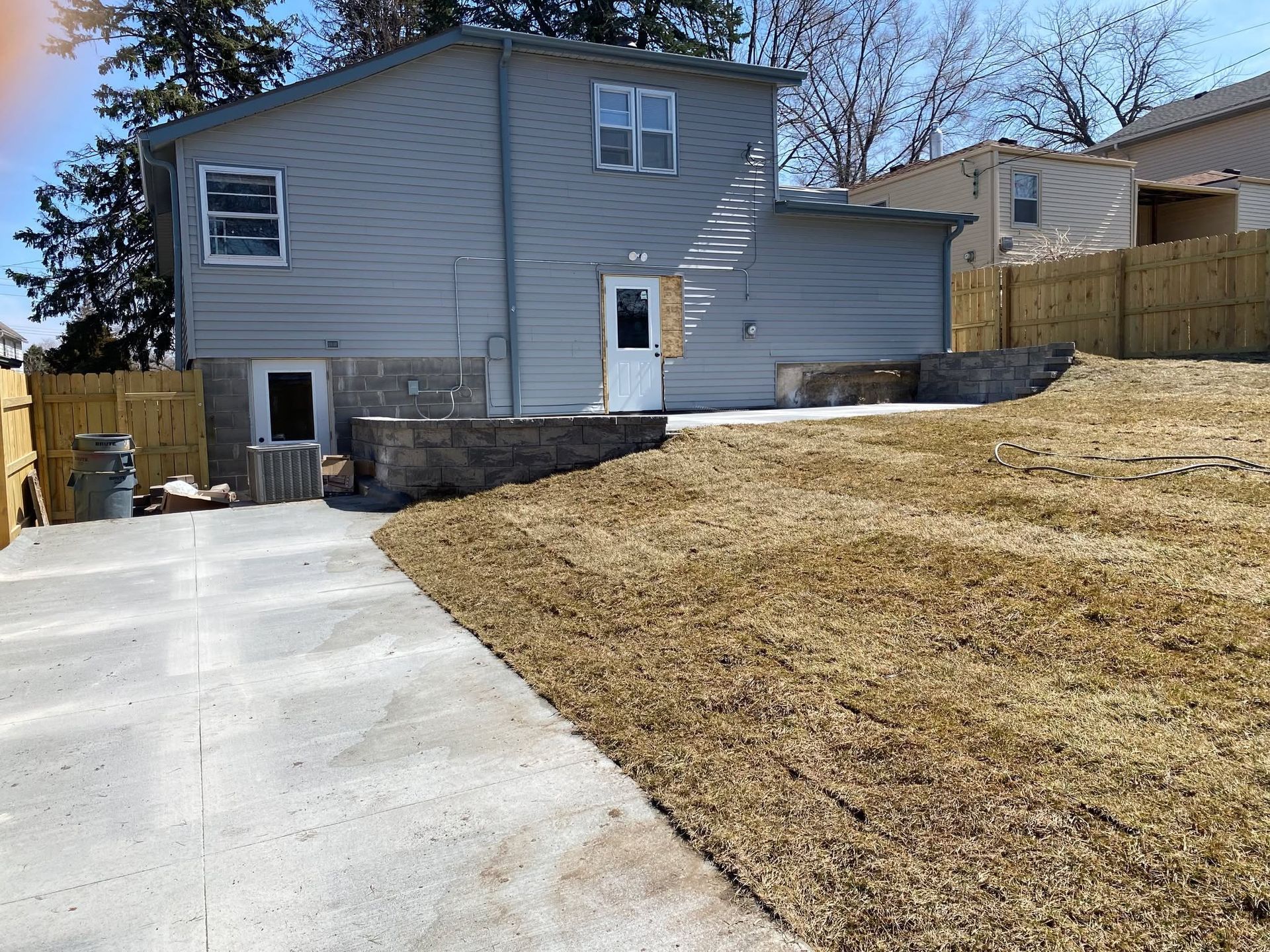 A house is sitting on top of a grassy hill next to a driveway.