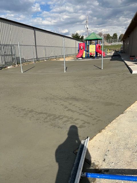A concrete driveway with a playground in the background.