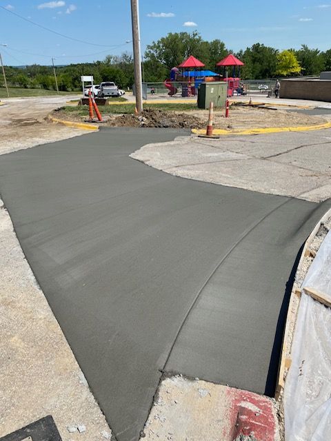 A concrete driveway is being built next to a playground.