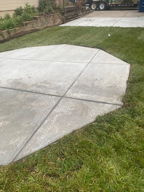 A concrete driveway with a truck parked in the background.