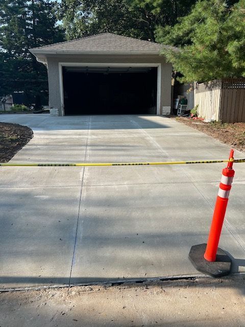 A concrete driveway with a garage in the background