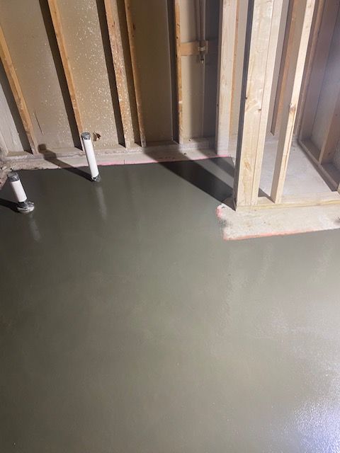 A concrete floor is being poured in a room under construction.