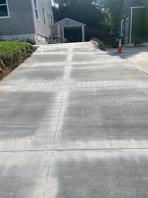 A concrete driveway leading to a house with a garage in the background.