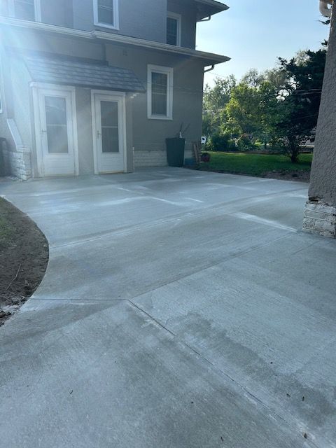 A concrete driveway in front of a house with the sun shining through the windows.