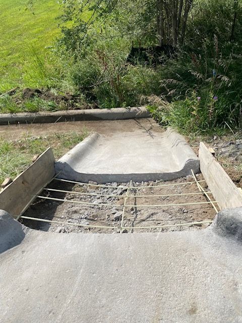 A concrete ramp is being built next to a grassy field.