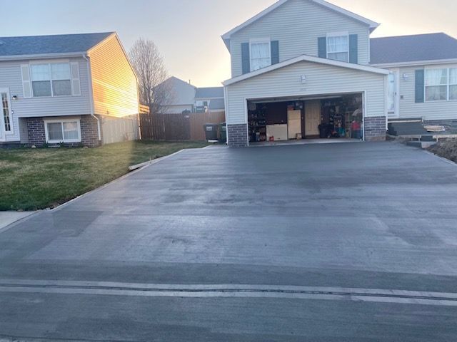 A concrete driveway leading to a house with a garage.